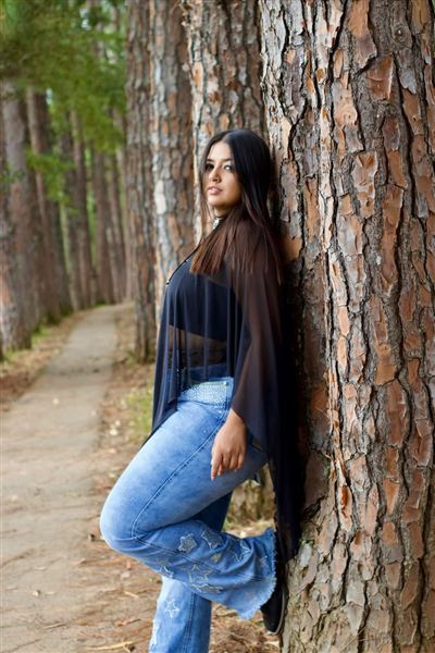 Ensaio individual de mulher encostada em uma árvore no bosque