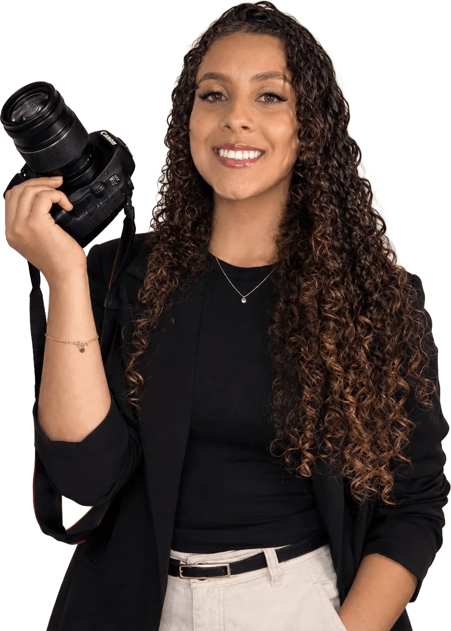 A fotógrafa Eduarda sorrindo com a câmera na mão