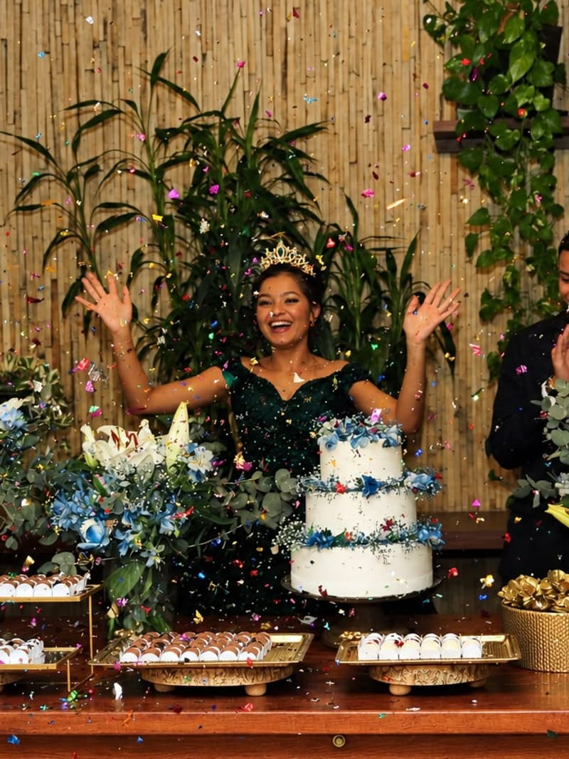 Aniversariante de coroa comemorando com chuva de confete na mesa do bolo